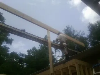Carpenter setting a ridge beam over a new addition frame — Ice Dam Removal by Roofing Brothers in Georges Mills