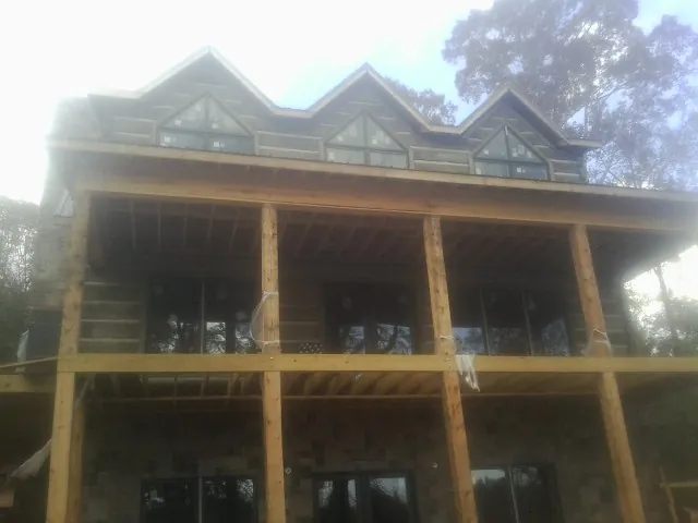 Dormers and porch framing on a large log home under construction — Roof Coating work by our crew in Georges Mills