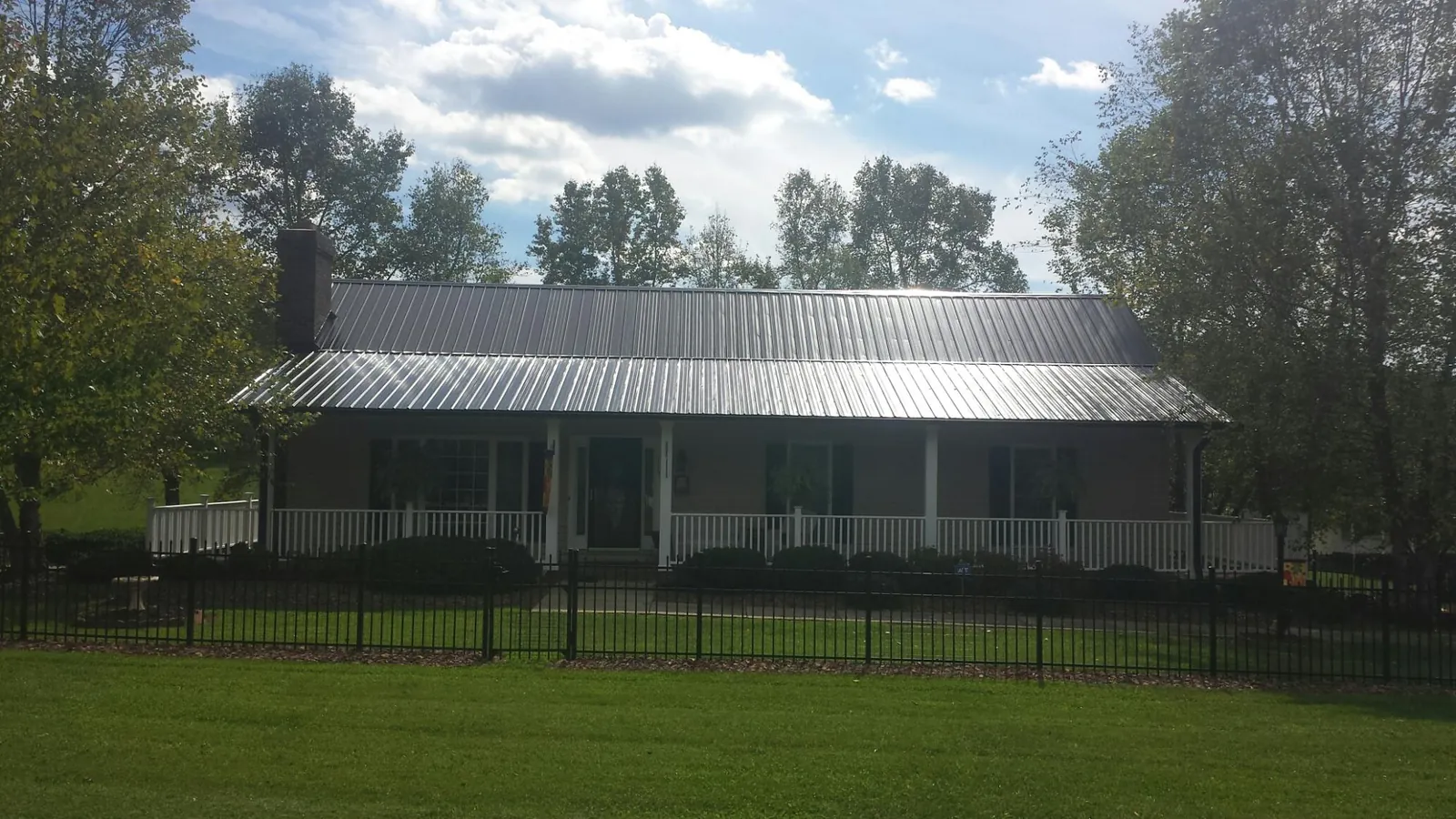 Gray metal roof on a brick ranch with a full width front porch — Gutter Guard Installation work by our crew in Georges Mills