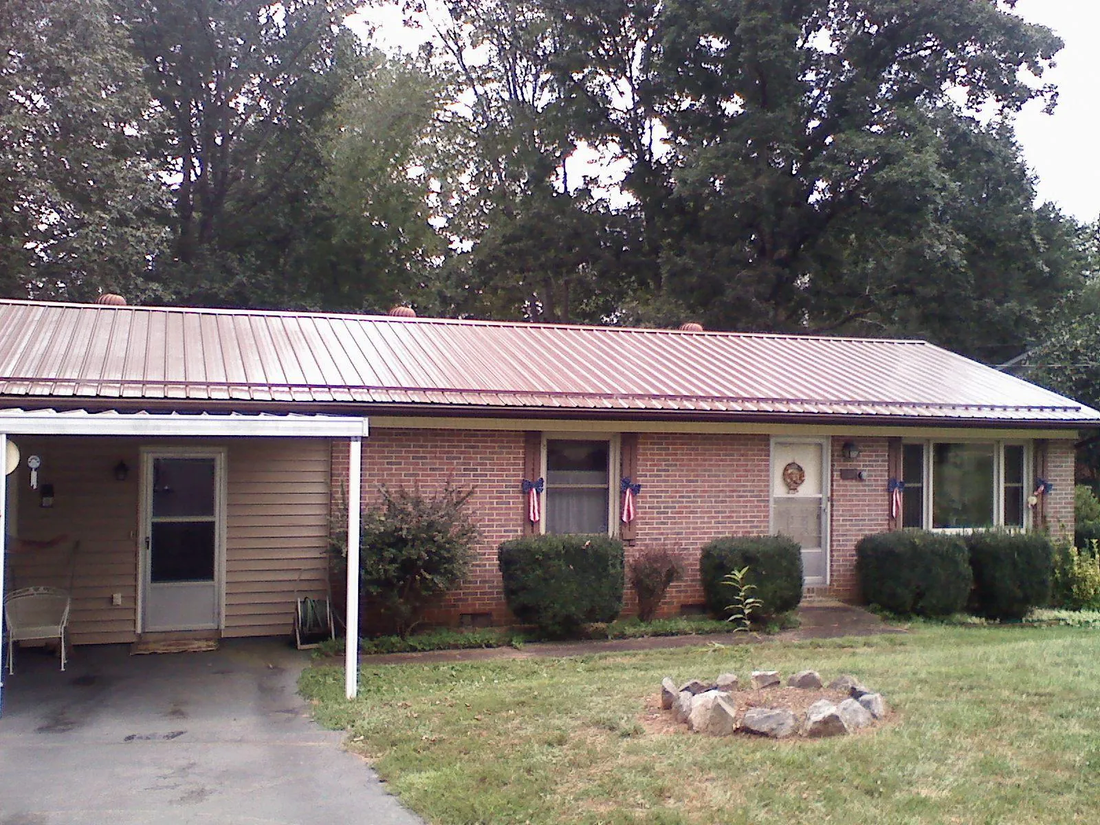 Bronze metal roof and carport on a brick ranch home — Roof Repair work by our crew in Georges Mills