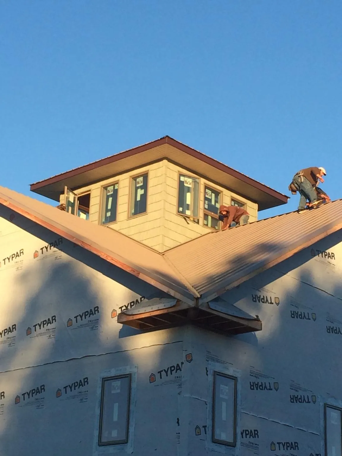 Roofers working around a rooftop cupola on a new metal roof at sunset — Roof Waterproofing in Georges Mills by Roofing Brothers